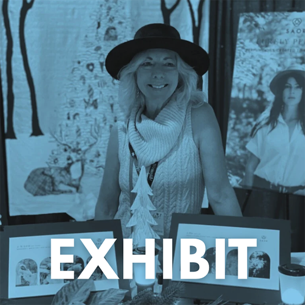 A middle aged woman in a hat and sweater standing behind a table of items she is selling at Winterfair